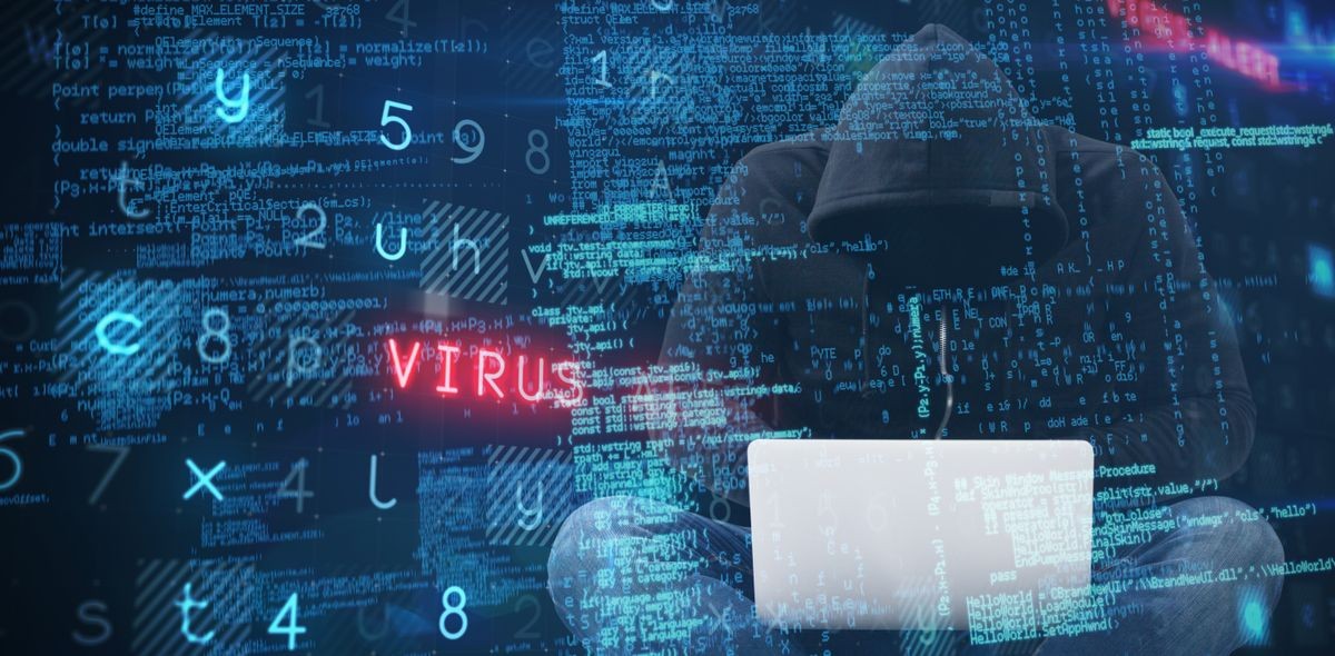 Male hacker using laptop while sitting against virus background